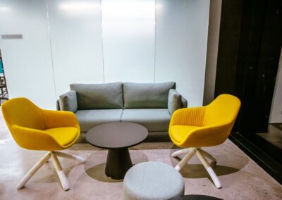 Lounge seating with a sofa, two yellow chairs, and a round table.