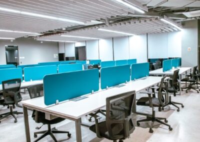 Open-plan office with rows of desks, blue dividers, and rolling chairs.
