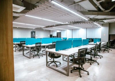 Open-plan office with rows of desks, blue dividers, and rolling chairs.