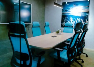 Modern meeting room with a table, office chairs, wall art, and a screen.
