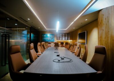 Modern conference room with a long table, leather chairs, and a large screen.