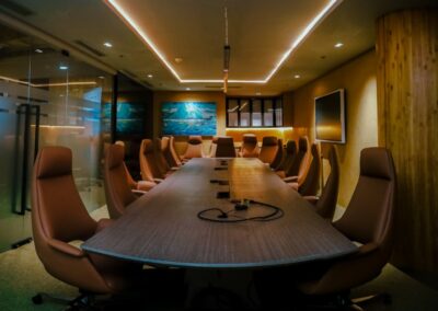 Modern conference room with a long table, leather chairs, and a large screen.