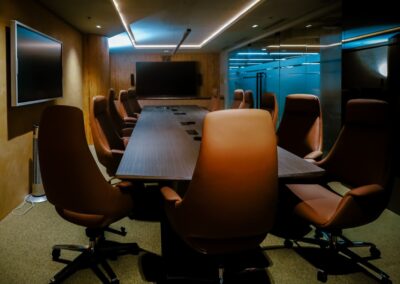 Modern conference room with a long table, leather chairs, and a large screen.