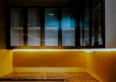 Modern office kitchenette with marble countertops and under-cabinet lighting.