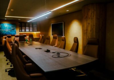 Modern conference room with a long table, chairs, and ambient lighting.