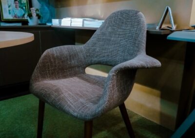 Modern office corner with an upholstered chair, desk, and decorative shelves.