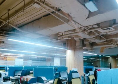 Open-plan office with desks, chairs, and overhead ductwork.