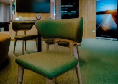 Modern office seating area with chairs, tables, and a presentation screen.