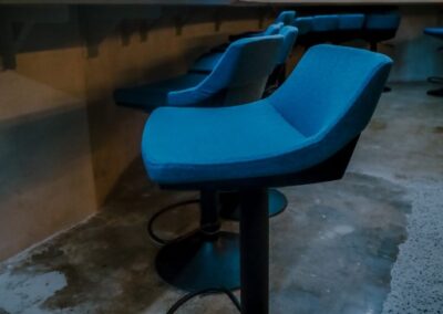 Row of blue bar stools along a counter in a modern office space.