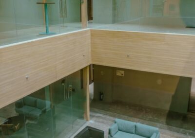 Modern office atrium with glass railings, seating area, and lounge furniture.