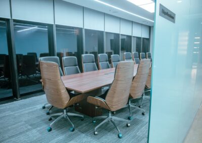 Glass-walled conference room with a long table and office chairs.