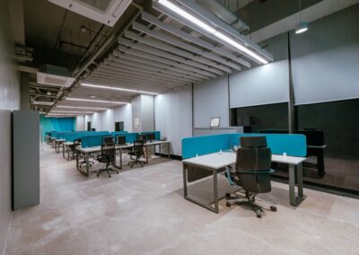 Open-plan office with rows of desks, blue dividers, and rolling chairs.