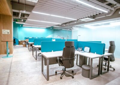 Open office workspace with desks, blue dividers, and office chairs.