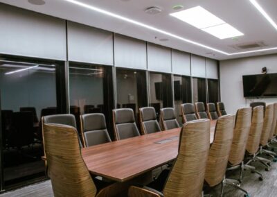 Conference room with a long table and high-back office chairs.