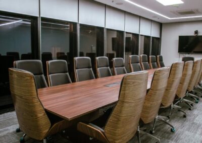 Conference room with a long table and high-back office chairs.
