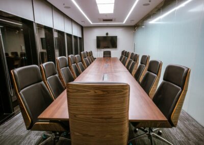 Conference room with a long table and high-back office chairs.