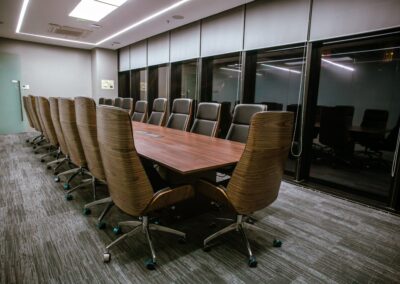 Conference room with a long table and high-back office chairs.