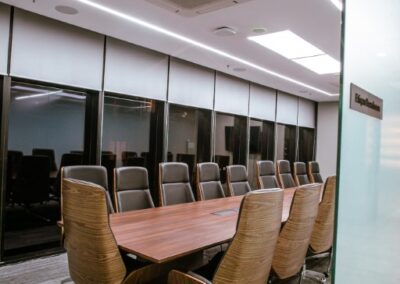 Conference room with a long table and high-back office chairs.
