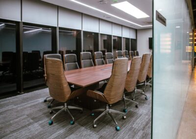 Conference room with a long table and high-back office chairs.