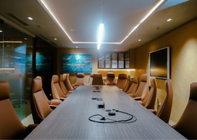 Modern conference room with a long table, leather chairs, and a large screen.