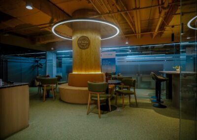 Modern office lounge with tables, chairs, and circular ceiling lighting.
